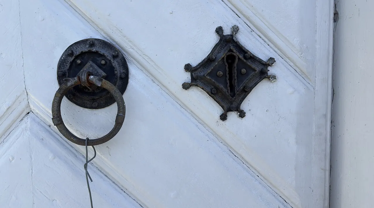 Een houten kerkdeur met sleutelgat en klink.